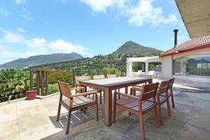 a wooden table and chairs on a patio with mountains at Suite SolVista in Cape Town