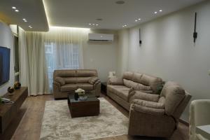 a living room with two couches and a tv at kornfil guest house in New cairo
