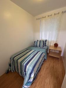 a bedroom with a bed with a striped comforter and a window at 2-Storey Town House 2 Bedroom in Conel