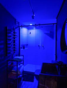 a dark room with a bathroom with blue lighting at Domo nas Alturas! Lareira, Hidro e Céu Estrelado in Rancho Queimado +21 photos