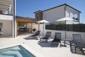 a patio with chairs and umbrellas and a swimming pool at Villa D&J in Vodnjan