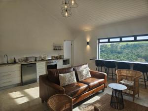 a living room with a leather couch and a kitchen at Podium Farm Stay in Swellendam +3 photos