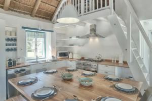 a kitchen with a wooden table with plates on it at Cape Creek Cottage, Luxury Coastal Getaway in Struisbaai +42 photos