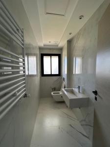 a white bathroom with a sink and a toilet at Luxury apartments in Hiboun