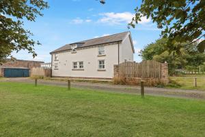 a white house with a fence in a yard at Doray House - North East Escapes in Newton by the Sea