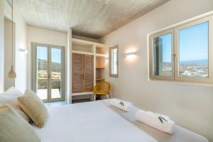 a bedroom with a white bed with windows at Salt n Sky Vivlos Naxos in Vívlos