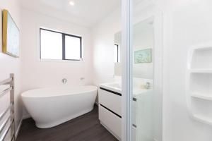 a white bathroom with a tub and a sink at Ski, Bike, Eat, Swim, Relax. in Methven +25 photos