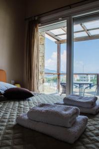 a bedroom with a bed with pillows and a large window at Petritis Villas in Iraklitsa