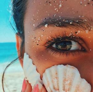 kobieta trzymająca muszlę przed twarzą na plaży w obiekcie Lorenzo Sea Loft Riccione apartment w mieście Riccione