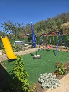 a playground with three swings on a green lawn at Yellow hill Batinac in Ćuprija