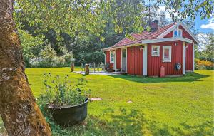 a small red house in a yard with a tree at Pet Friendly Home In Malmbäck With Wifi in Malmbäck