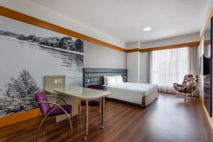 サンパウロにあるWyndham Garden São Paulo Convention Nortelのベッドとテーブルと椅子のあるホテルの部屋 +37枚の写真