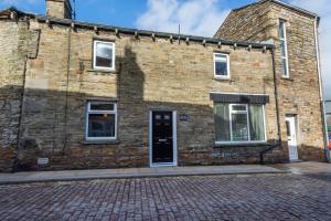 un edificio de ladrillo con una puerta negra en una calle en The Old Penny Bank, en Hawes 12 fotos más