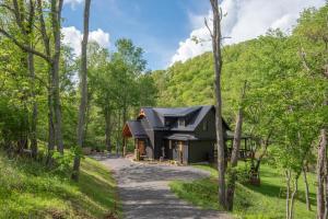 a house in the woods with a black roof at Lux Riverfront Retreat- Hot Tub, Game Room, Views! in Lansing