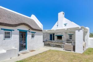 a white house with a patio and a table at Cape Creek Cottage in Struisbaai