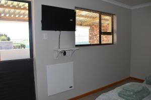 ein Zimmer mit Fernseher, Bett und Fenster in der Unterkunft Nuwepos in Vanrhynsdorp