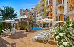 eine Gruppe von Stühlen und Sonnenschirmen neben einem Gebäude in der Unterkunft Sweet Homes 2 Apartments in Sonnenstrand