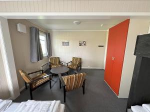 a room with chairs and a table and a red door at Karivollen Overnatting in Melhus