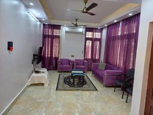 a living room with purple furniture and purple curtains at Bangalore Chalet in Bangalore