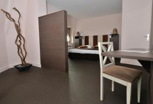 a bedroom with a bed and a table with a chair at Hotel Des Bains in Granville