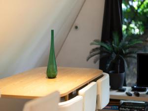 a green vase sitting on top of a wooden table at Lanaken Lakeside Cabin Stay in Lanaken