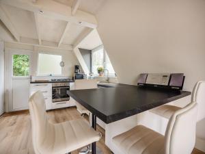 a kitchen with a black counter top and white chairs at Lanaken Lakeside Cabin Stay in Lanaken +23 photos