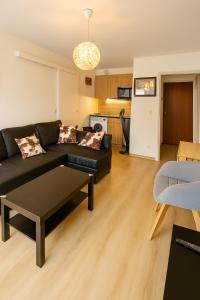 a living room with a black couch and a table at Appartement neuf Beautiful Villers 1-4 pers avec parking privé et à 200 m plage in Villers-sur-Mer