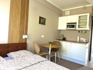 a bedroom with a bed and a table and a kitchen at Apartament Motyl in Warsaw