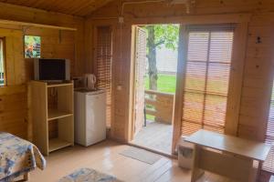 um quarto com uma cabina de madeira com um frigorífico e um alpendre em Poilsio nameliai Jūros 67 em Šventoji