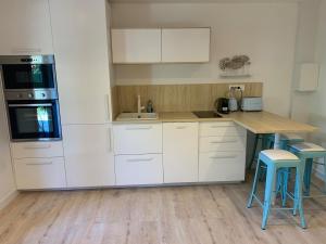 a kitchen with white cabinets and a counter with stools at Magnifique appartement proche de la plage in Hyères +16 photos
