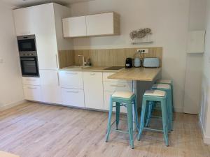 a kitchen with white cabinets and a wooden table and stools at Magnifique appartement proche de la plage in Hyères