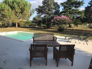 a picnic table and two chairs next to a pool at Maison in Lamonzie-Saint-Martin