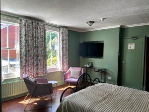 a bedroom with a bed and two chairs and a television at Balham Lodge in London