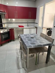 a kitchen with red cabinets and a table and chairs at Appartement meublé in Sukrah