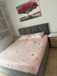 a bedroom with a bed with pink sheets and a tree at Apartament Astir in Tirana