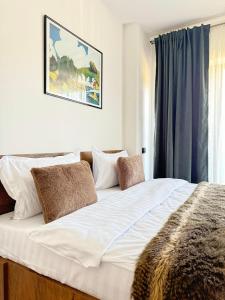 a large bed with white sheets and brown pillows at Cara Grand Chalet in Braşov