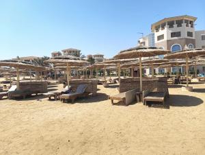a beach with chairs and umbrellas on the sand at Royal Beach Resort in Hurghada
