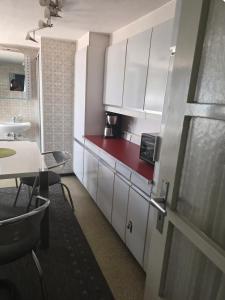 cocina con armarios blancos y encimera roja en Ferienzimmer in bad friedrichshall, en Bad Friedrichshall