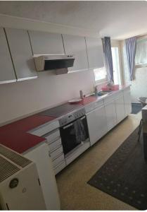 Una cocina con gabinetes blancos y un horno de estufa. en Ferienzimmer in bad friedrichshall, en Bad Friedrichshall