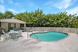 a swimming pool with chairs and a table and a fence at Shell Yeah 3 Story Condo On AMI in Holmes Beach