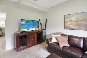 a living room with a couch and a flat screen tv at Shell Yeah 3 Story Condo On AMI in Holmes Beach