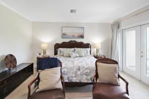 a bedroom with a bed and two chairs at Shell Yeah 3 Story Condo On AMI in Holmes Beach +42 photos