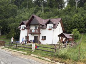 a house with people standing in front of it at Casa Vanatorului Buzaiel in Vama Buzăului