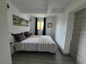a bedroom with a bed in a white room at Ti cocon nature in Sainte-Anne