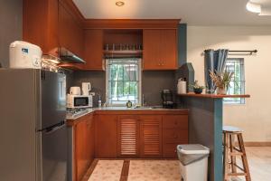 a kitchen with wooden cabinets and a stainless steel refrigerator at Areca Holiday Home 8, Bangtao Beach in Ban Thalat Choeng Thale