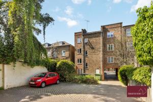 a red car parked in front of a building at Twickenham - One Bedroom Flat - With Parking in Twickenham