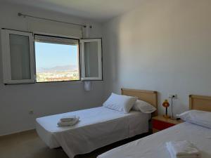 two beds in a room with a window at San Miguel Apartamentos in El Ejido