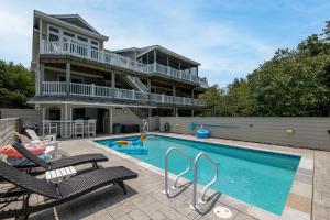 a house with a swimming pool in front of a house at Beach Cabana in Southern Shores