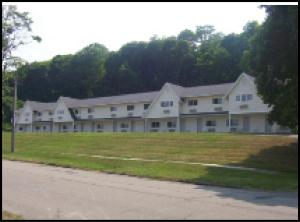 a large white building with a field in front of it at The Falls Motel in Watkins Glen