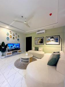 a living room with a white couch and a tv at Cozy 1BR Designer Apartment, Gulberg Greens in Islamabad